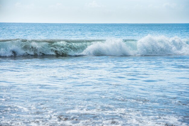 Kalm blauw zeegezicht met witte surfgolf op de voorgrond