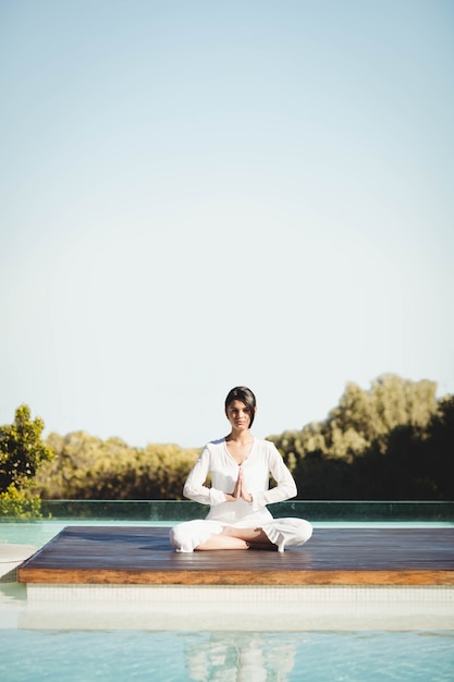 Kalm brunette die yoga doet bij het zwembad