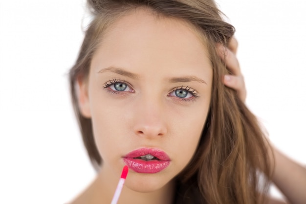 Kalm donkerbruin model dat roze glans op haar lippen toepast