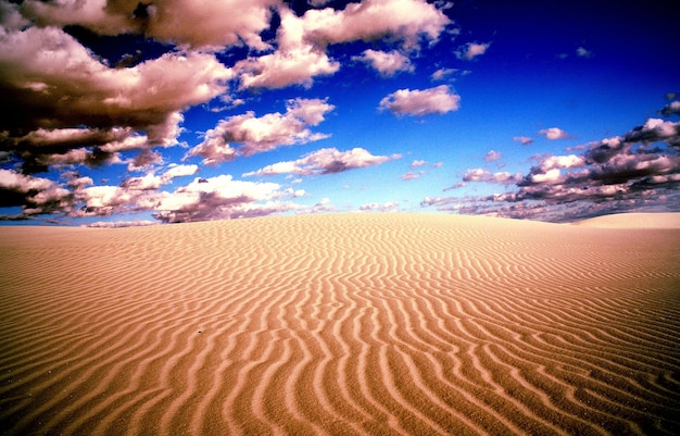 Foto kalm zandstrand onder blauwe lucht en wolken.