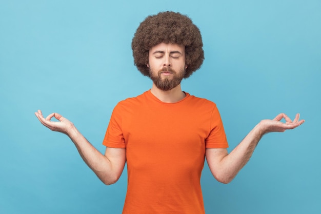 Kalme meditatieve knappe man met gesloten ogen en yogagebaar pose