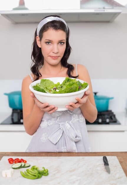 Kalme mooie brunette die gezonde salade houdt