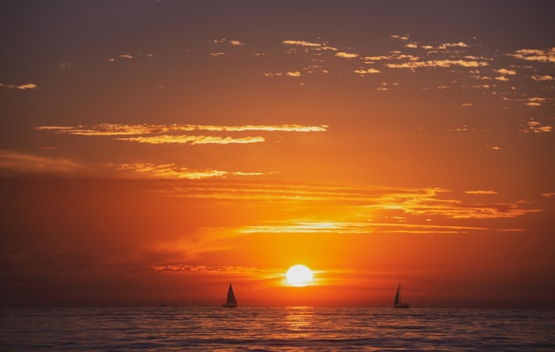 Kalme zee met zonsonderganghemel en zon door de wolken over oceaan en hemelachtergrondzeegezicht