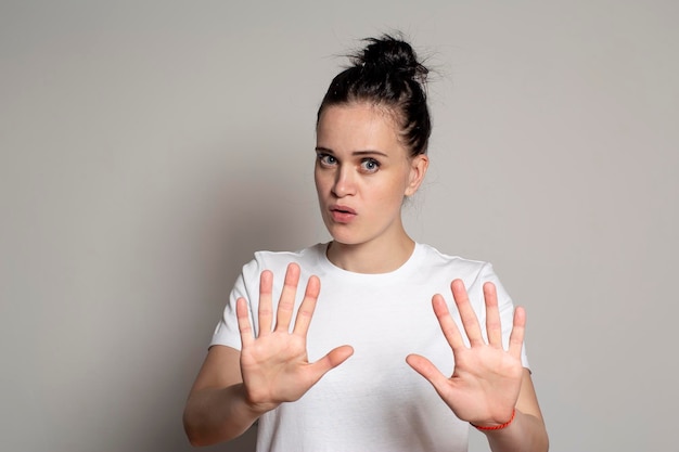 Kalme zelfverzekerde jonge vrouw stak zijn handpalmen naar voren als bescherming om iemand te kalmeren