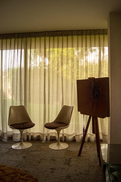 Kamer met twee stoelen vintage meubelgordijn achter waardoor het licht door kan