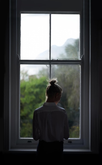 Kamer met uitzicht Een mooie jonge vrouw die bij een raam staat