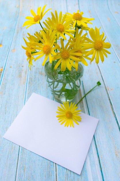 Foto kamille bloemen in een vaas en een envelop briefkaart bericht uitnodigingkopieer ruimte