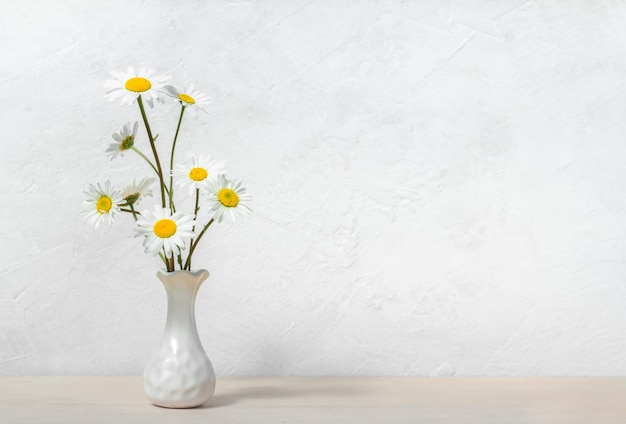 Kamille in vaas op witte bloemen als achtergrond