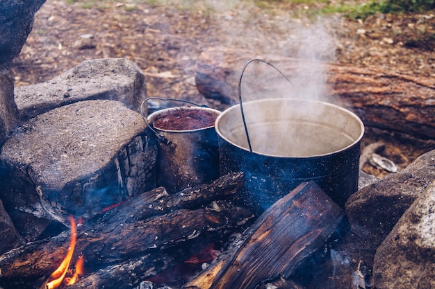 Kampeerpot in brand met koffie en heet water voor thee of stamppot. Buiten stomen eten. Wildlife lifestyle koken heerlijke maaltijd, Copyspace Rechtenvrije Stockafbeeldingen