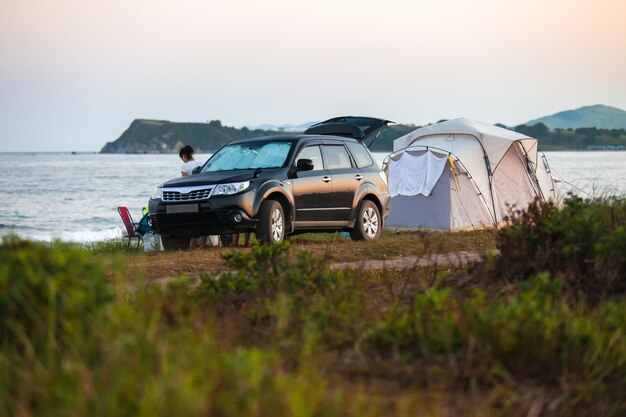 Kamperen aan zeekust. Grote tent en zwarte crossover