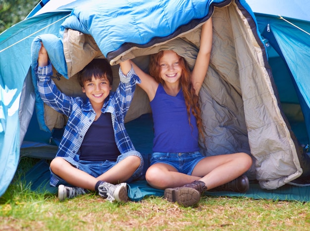 Foto kamperen en genieten portret van een jonge broer en zus die in hun tent zitten