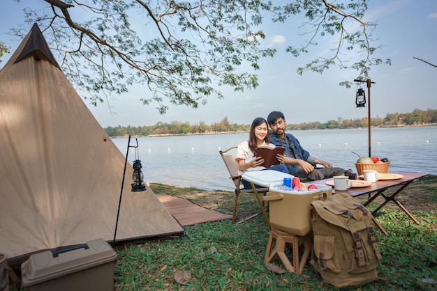 Kamperen en reizen concept Jong koppel backpackers lezen samen een boek terwijl ze kamperen bij het meer