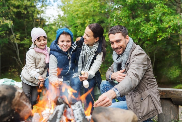 kamperen, reizen, toerisme, wandelen en mensen concept - gelukkige familie marshmallow roosteren boven kampvuur