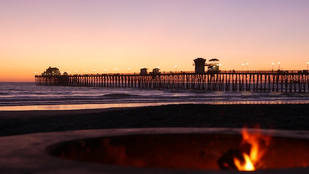 Kampvuurplaats door pijler Californië de V.S. Kampvuur branden op oceaan strand vreugdevuur vlam schemering zonsondergang