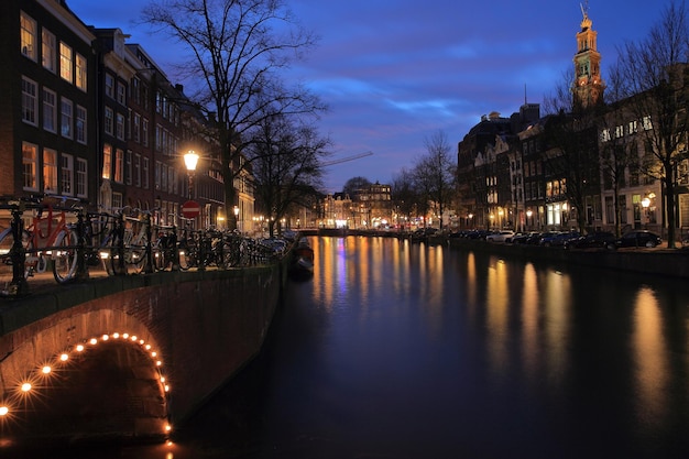 Kanaal te midden van verlichte gebouwen tegen de hemel in de schemering