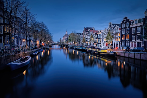 Kanaal te midden van verlichte stadsgebouwen tegen de hemel in de schemering