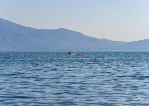 Kanovaarders gaan op een zonnige dag per kano in de Egeïsche Zee op een achtergrond van een klif in Griekenland