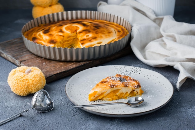 Kant-en-klaar stuk verse zoete gelaagde pompoentaart bestrooid met poedersuiker op een bord op tafel. Thanksgiving-traktatie