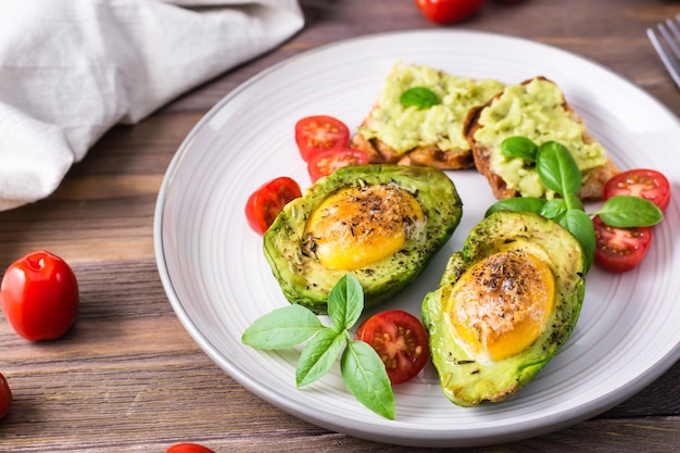 Kant-en-klaar voorgerecht gebakken avocado met ei, toast en cherrytomaatjes op een bord op een houten tafel. Gezond eten. Flexitarisch dieet. Detailopname