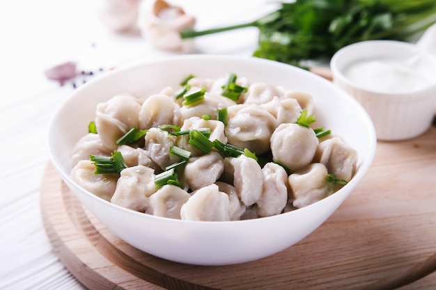 Kant en klare dumplings op een wit bord met uien en kruiden