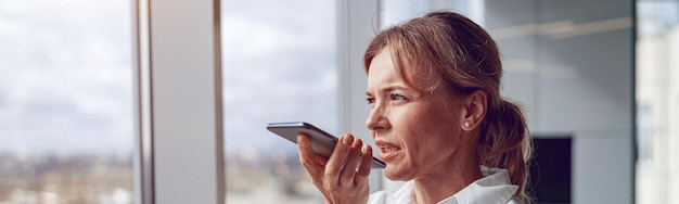 Kantoor bedrijfsconcept portret van knappe volwassen vrouw met mobiele telefoon opname stemmassage