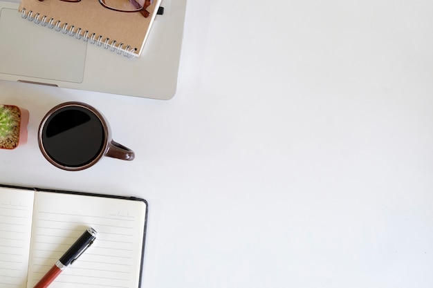 Kantoorbenodigdheden met werkruimte computer, pen, Kladblok papier, plant versieren en een kopje koffie op bovenaanzicht desk work.