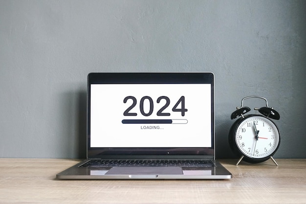 Kantoordesk met 2024 laadbalk op het scherm van de laptop voor een gelukkig nieuwjaarsconcept