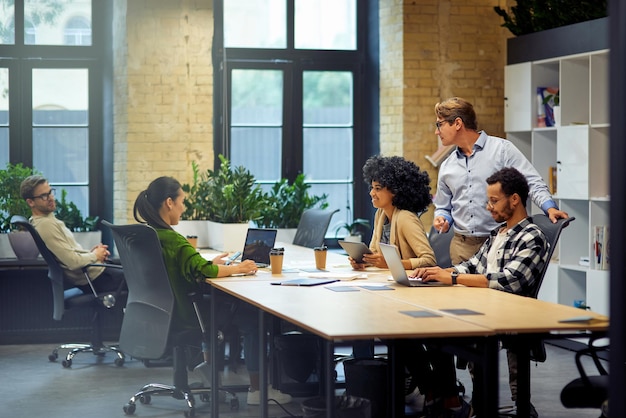 Kantoorlevensgroep van jonge multiraciale mensen die aan tafel zitten in een coworking-ruimte en