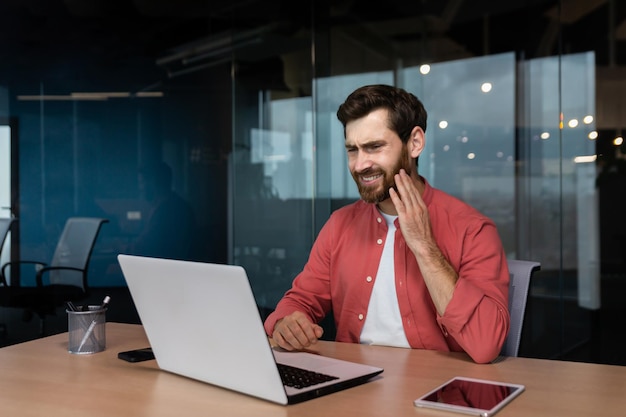 Kantoormedewerker heeft kiespijn, een zieke zakenman werkt op kantoor met een laptop, een man heeft een