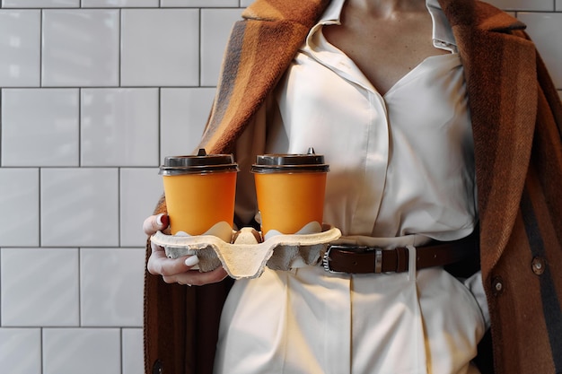 Kantoormedewerker houdt gele kopjes met koffie tegen de muur