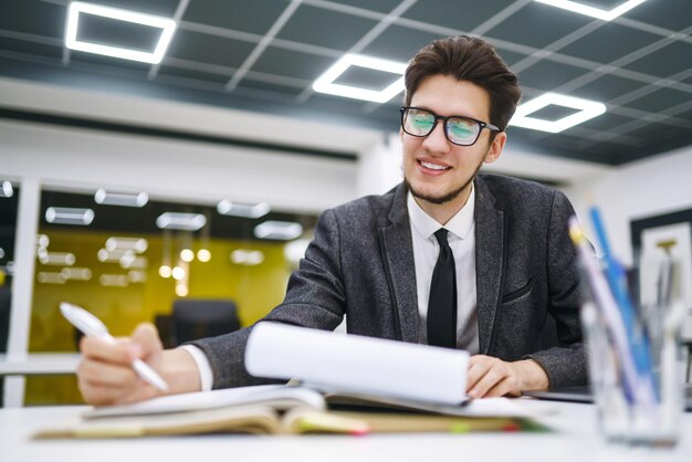 Kantoormedewerker met een bril leest documenten in een kantoormanager die werkt met een nieuw opstartproject