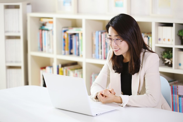 Kantoormedewerker vrouw die thuis werkt met een laptop online via internet met een stralende glimlach