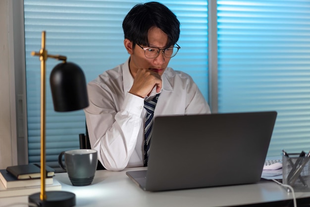 Kantoorpersoneel in de losse stropdas zit aan zijn bureau een papierwerk te lezen en op het notitieboekje te typen