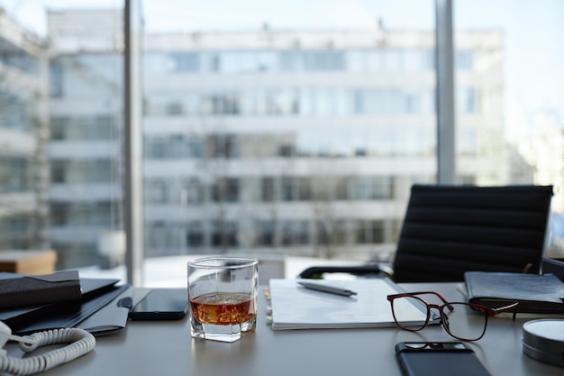 Kantoorruimte met whiskyglas op tafel tegen grote ramen