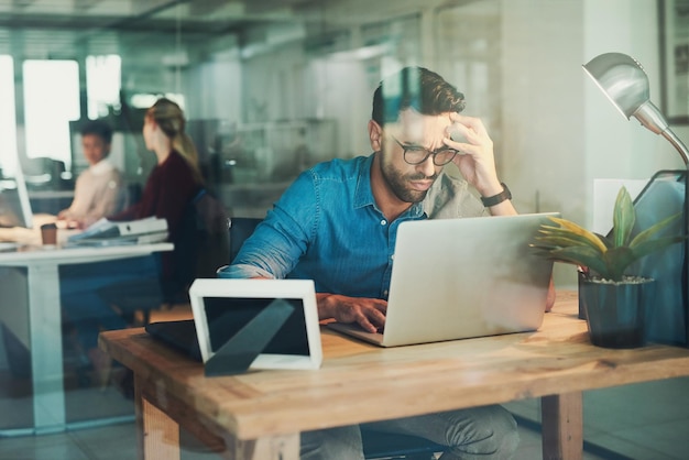 Kantoorstress en zakenman met laptop voor het schrijven van artikelen en onderzoek online voor nieuwsproject Journalist typen en schrijver met hoofdpijn van hard werken bij het herzien van persinformatie en lezen