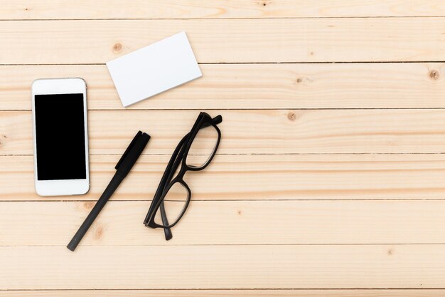Kantoorwerkruimte met smartphone-businesscardpen en bril op houten oppervlak