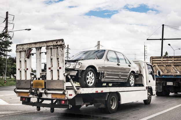 Kapotte auto op sleepwagen na verkeersongeval, onderweg