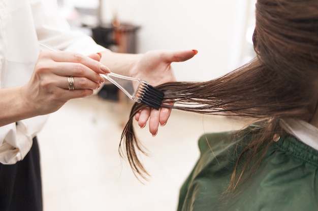 Kapper brengt een haarmasker aan op de vrouw in de schoonheidssalon. Botox en keratine rechttrekken procedure