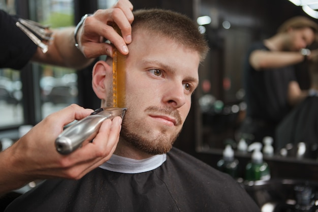 Kapper die een cliënt scheert bij de salon