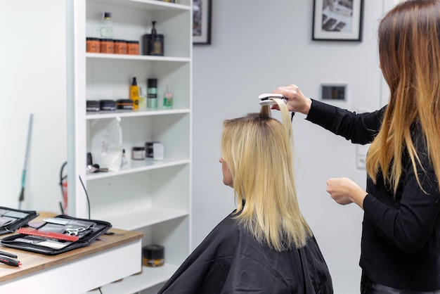 kapper doet stijlvolle styling aan vrouw in salon