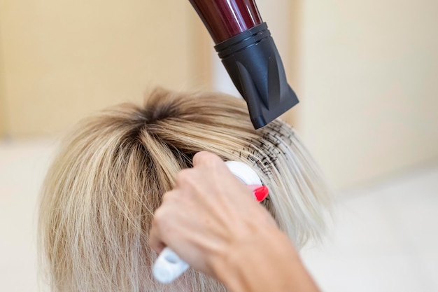 Kapper droogt nat haar, maakt haarstyling een föhn en kamt naar een blonde klant