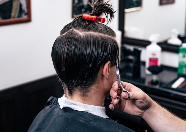 Kapper in Barbershop scheert haar elektrische auto tot jonge kerel hipper voor modieus kapsel.