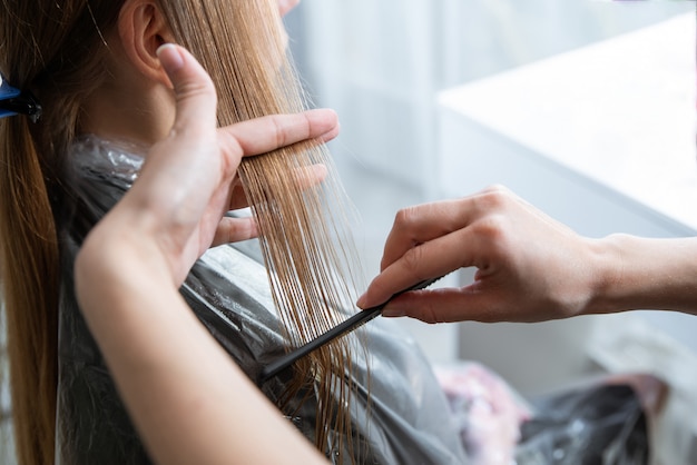 Kapper lang blond haar met borstel in de schoonheidssalon borstelen