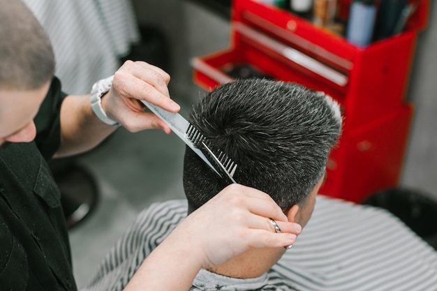 Kapper maakt een kapsel voor een volwassen man met grijs haar Barbershop concept