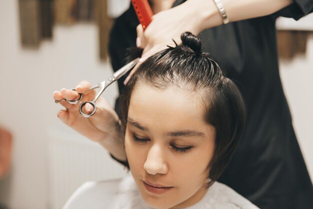 Kapper maakt een kapsel voor een vrouw in de salon De kapper knipt nat haar kammend met een kamcliënt met kort haar achteraanzicht