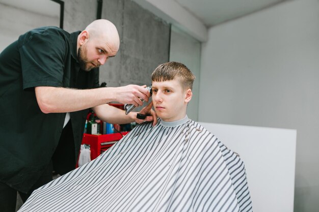 Kapper met tondeuse in de hand creëert een stijlvol kapsel voor een man Kapsel in barbershop-concept