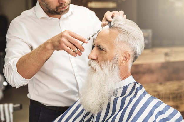 Kapper stijlvolle kapsel maken voor een knappe oude man in de kapperszaak