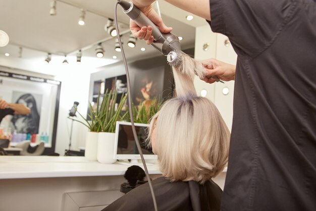 Kapper styling jonge vrouw haar in schoonheidssalon