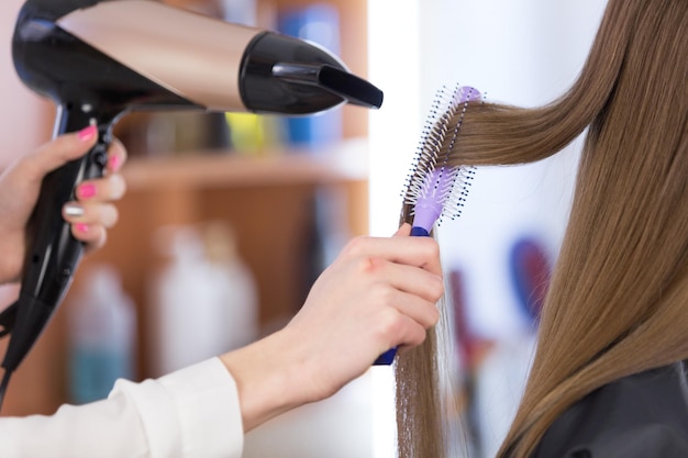 Kapper-stylist doet de styling bij het meisje, met behulp van haarstyling