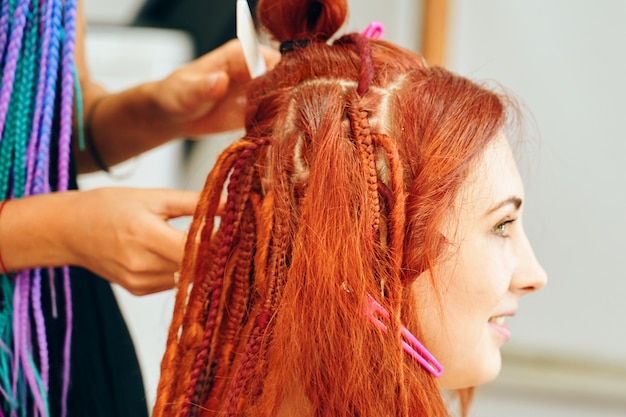 Kapper vlechten veilige dreadlocks. Mooi meisje dat trendy vlechten dreadlocks maakt. kanekalon